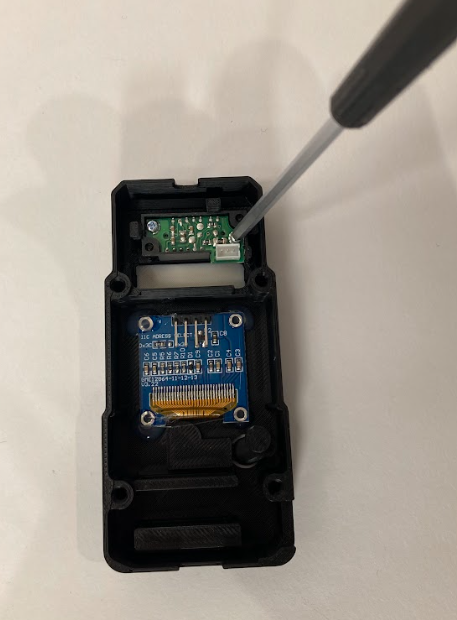 Using a screwdriver to insert the sensor into the trainer casing